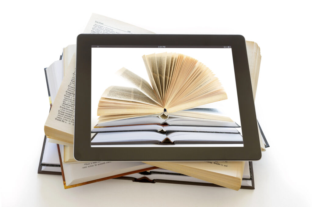Stack of open books with a digital tablet on top, showing an open book on its screen, symbolizing digital publishing.
