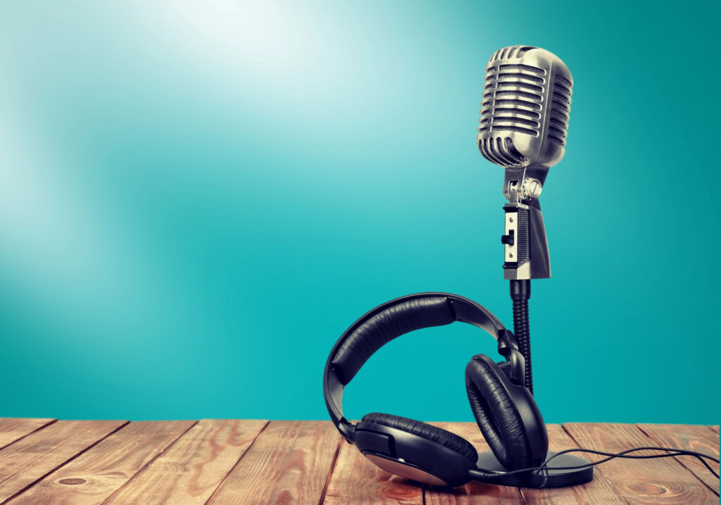Microphone and headset on a wooden table set against a gradient white and teal background.