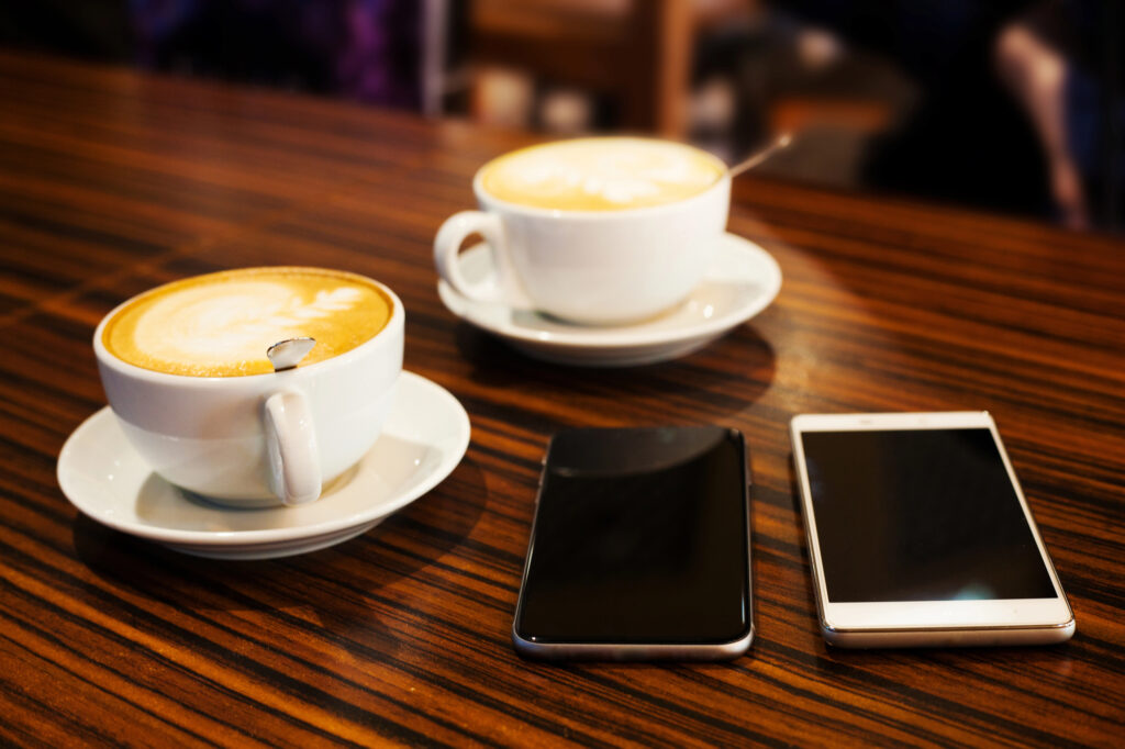 Two cups of coffee and two smartphones on a table, symbolizing connection and conversation.